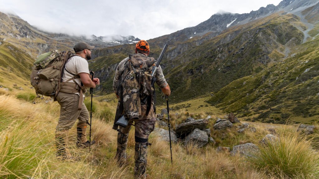 Two hunters stop to survey the valley during a hunt in New Zealand.