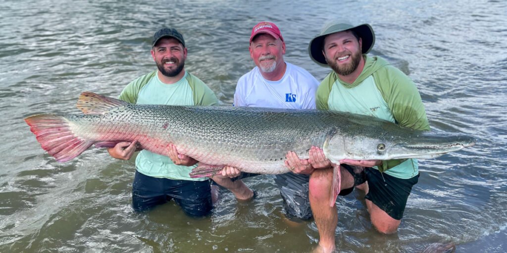 Bo and his brother and father hold a large Alligator Gar down in Texas.