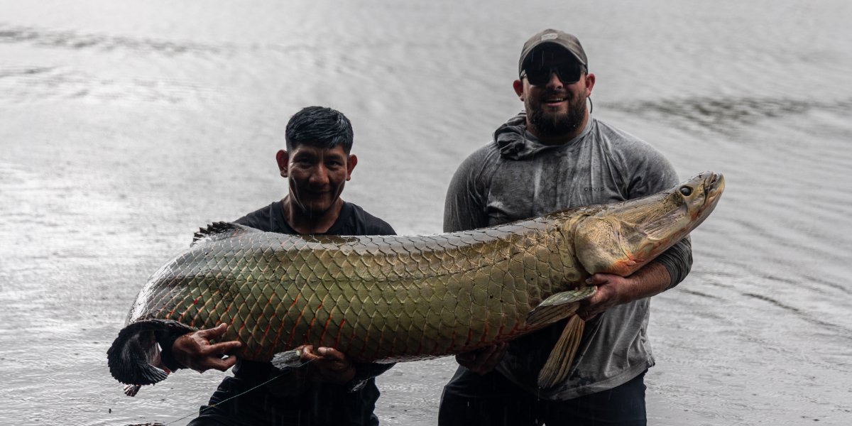 Bo and Keitus hold up an adult Arapaima.
